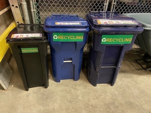 Three recycling toters of various sizes and colors lined up in a row.
