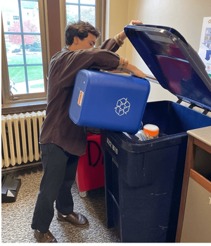 Student tipping personal recycling bin into large recycling toter.