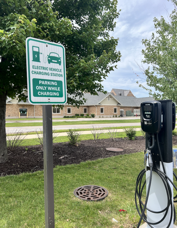 electric vehicle charger next to a sign that says "electric vehicle charging only while parking"